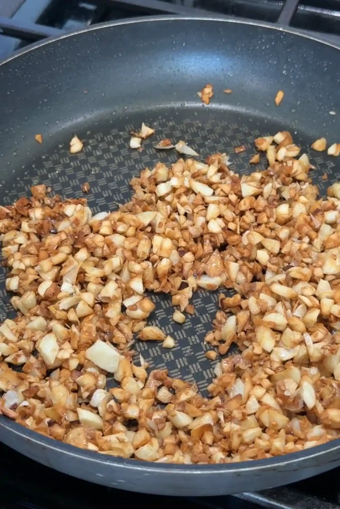 of minced garlic in a nonstick skillet after several more minutes of cooking, showing a deeper golden-brown color and crisped edges.