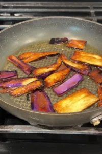 Eggplant slices frying in hot oil in a nonstick skillet,