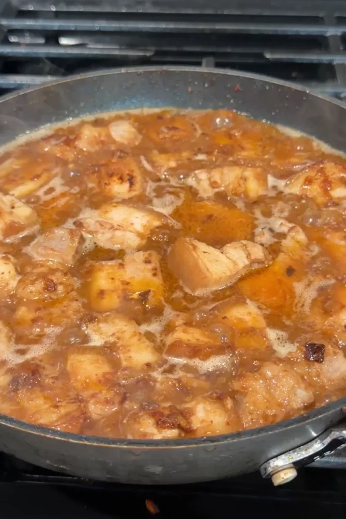 Pork belly simmering in a thin brown sauce after the water has been added.