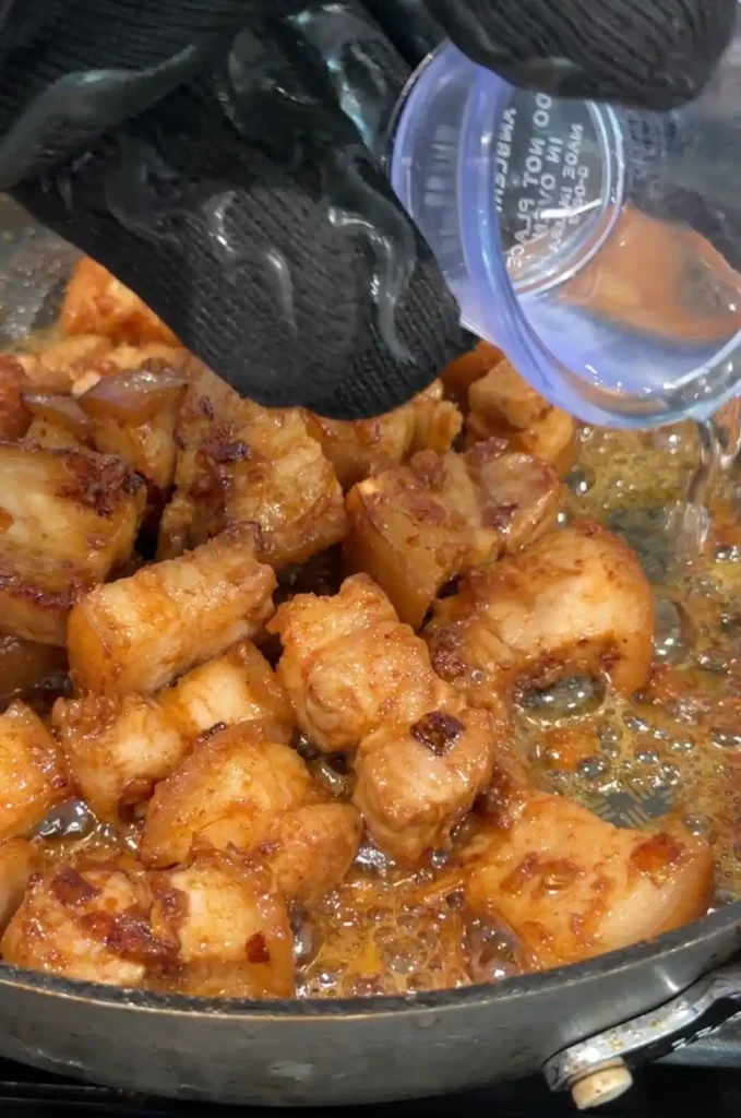 A small splash of vinegar being poured into the skillet.