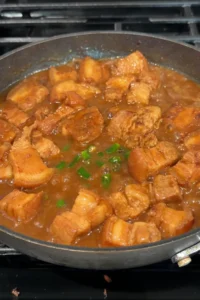 Chopped green chilies added to the simmering pork and sauce in the skillet.