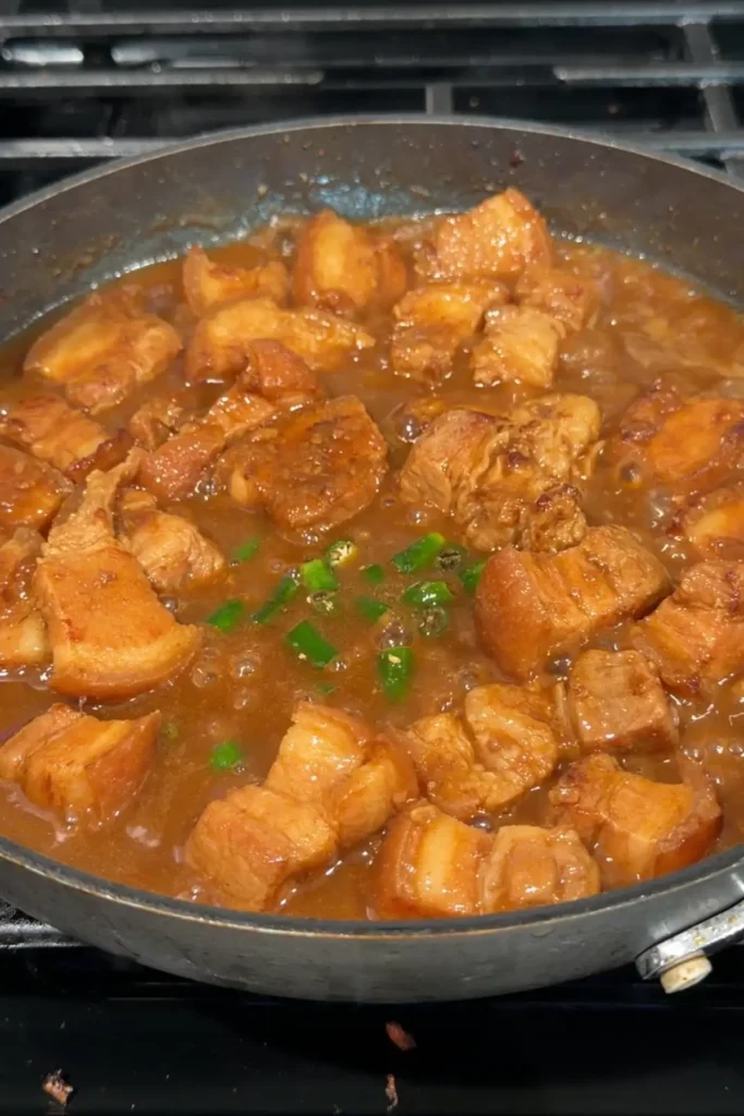 Chopped green chilies added to the simmering pork and sauce in the skillet.