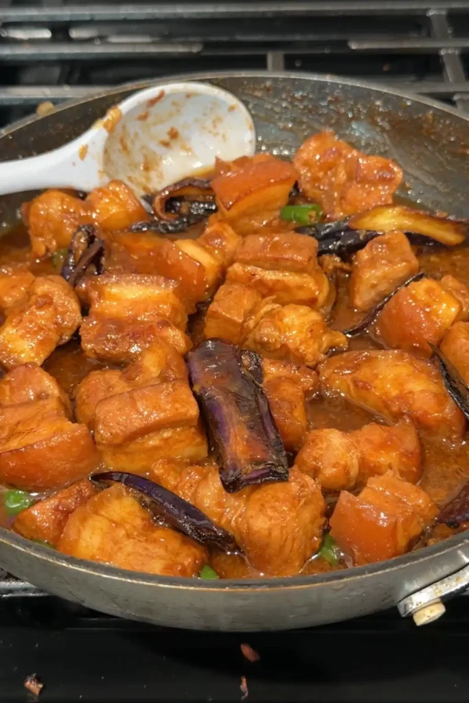 Finished pork binagoongan in the skillet, with browned eggplant folded into the glossy shrimp paste sauce.