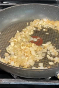 Chopped onion and garlic cooking together in a skillet until softened and lightly golden.