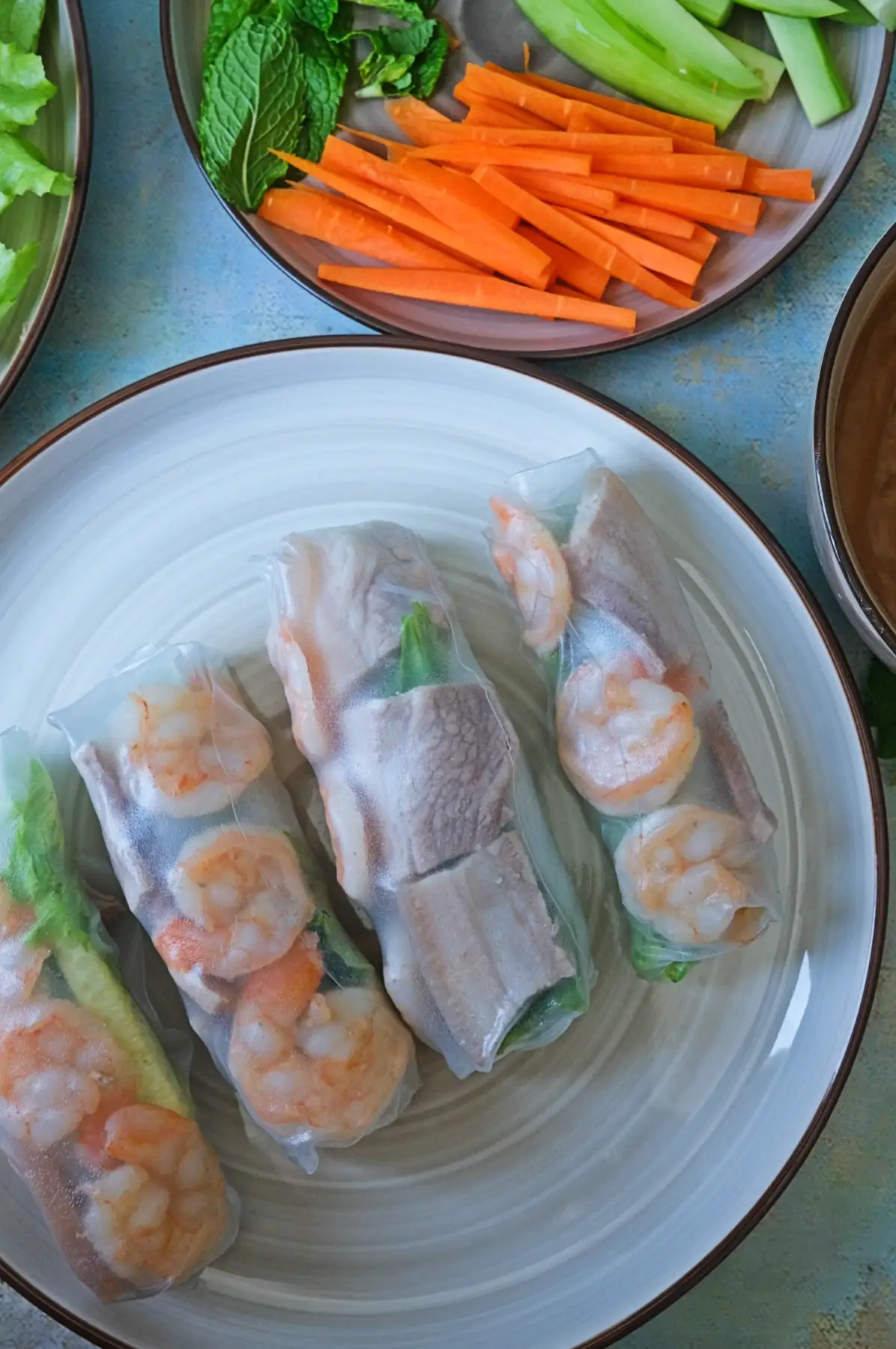 Fresh spring rolls with shrimp and pork on a plate with sliced carrots and cucumbers