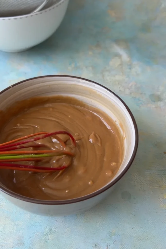 Creamy peanut sauce being whisked until smooth and thick