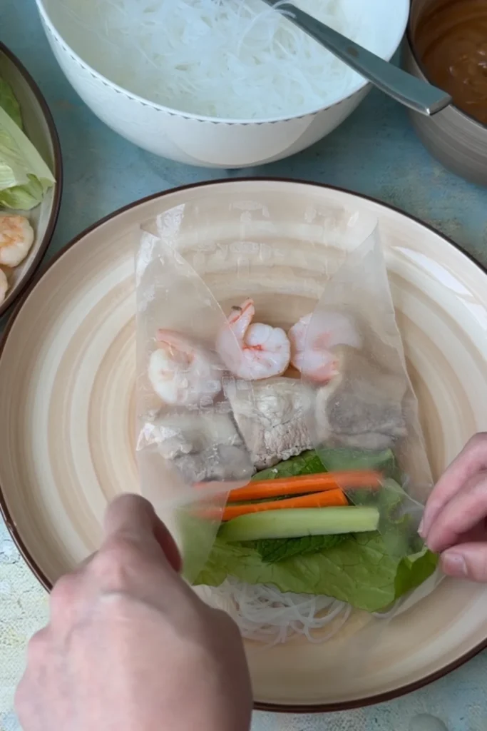 Rice paper wrapper folded with the sides tucked in over the filling before rolling