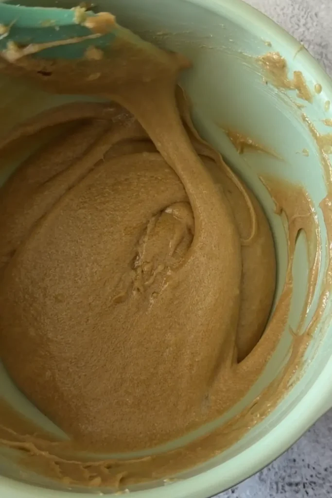 A smooth, glossy cookie dough after mixing in the egg, showing a thick and cohesive consistency.