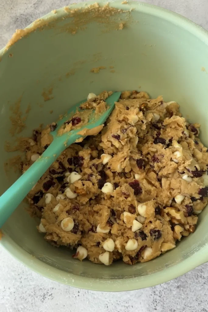 Fully mixed cookie dough with white chocolate chips, nuts, and cranberries evenly distributed throughout.