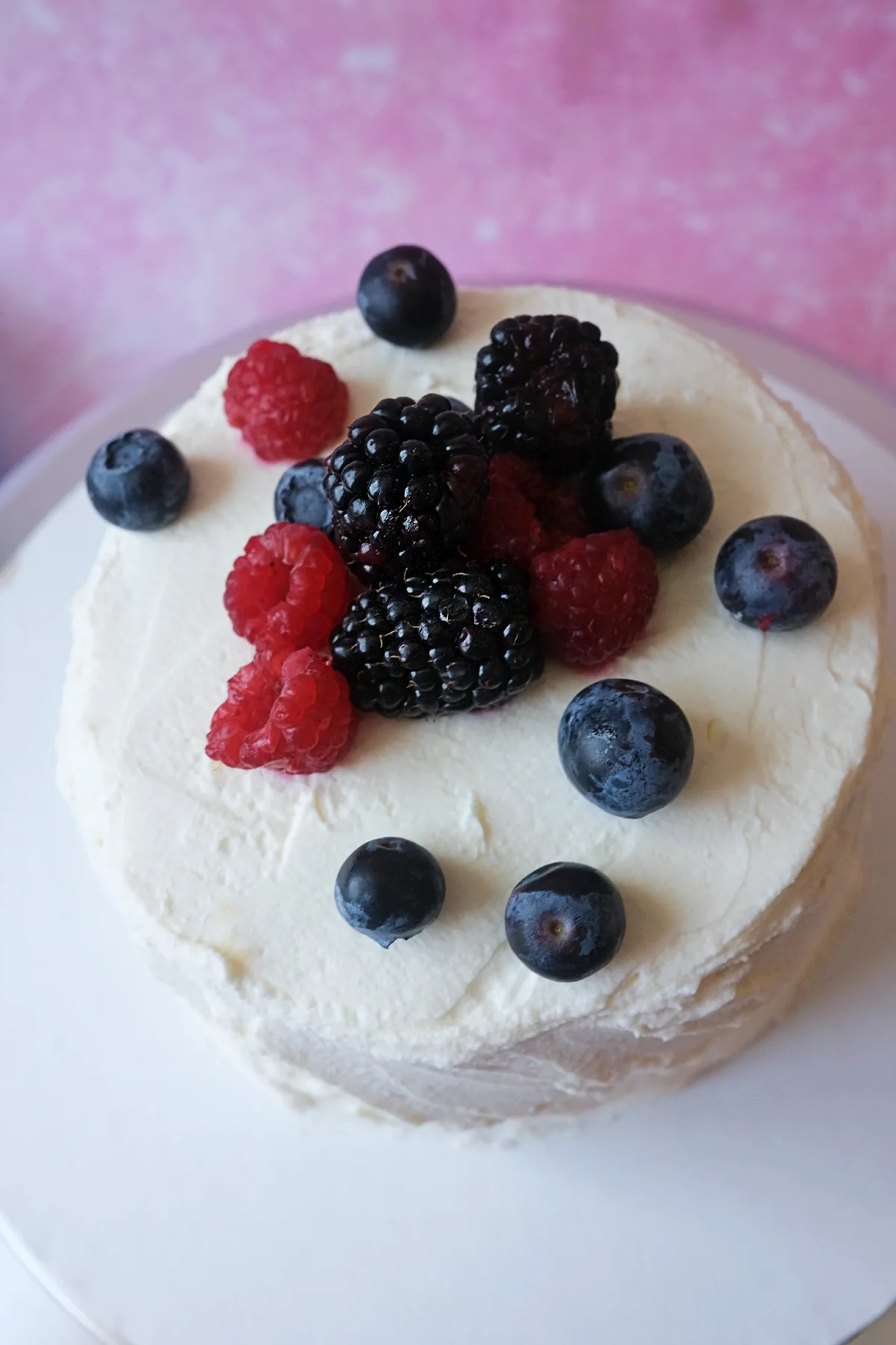 Berry chantilly cake topped with fresh raspberries, blueberries, and blackberries over fluffy mascarpone chantilly frosting.