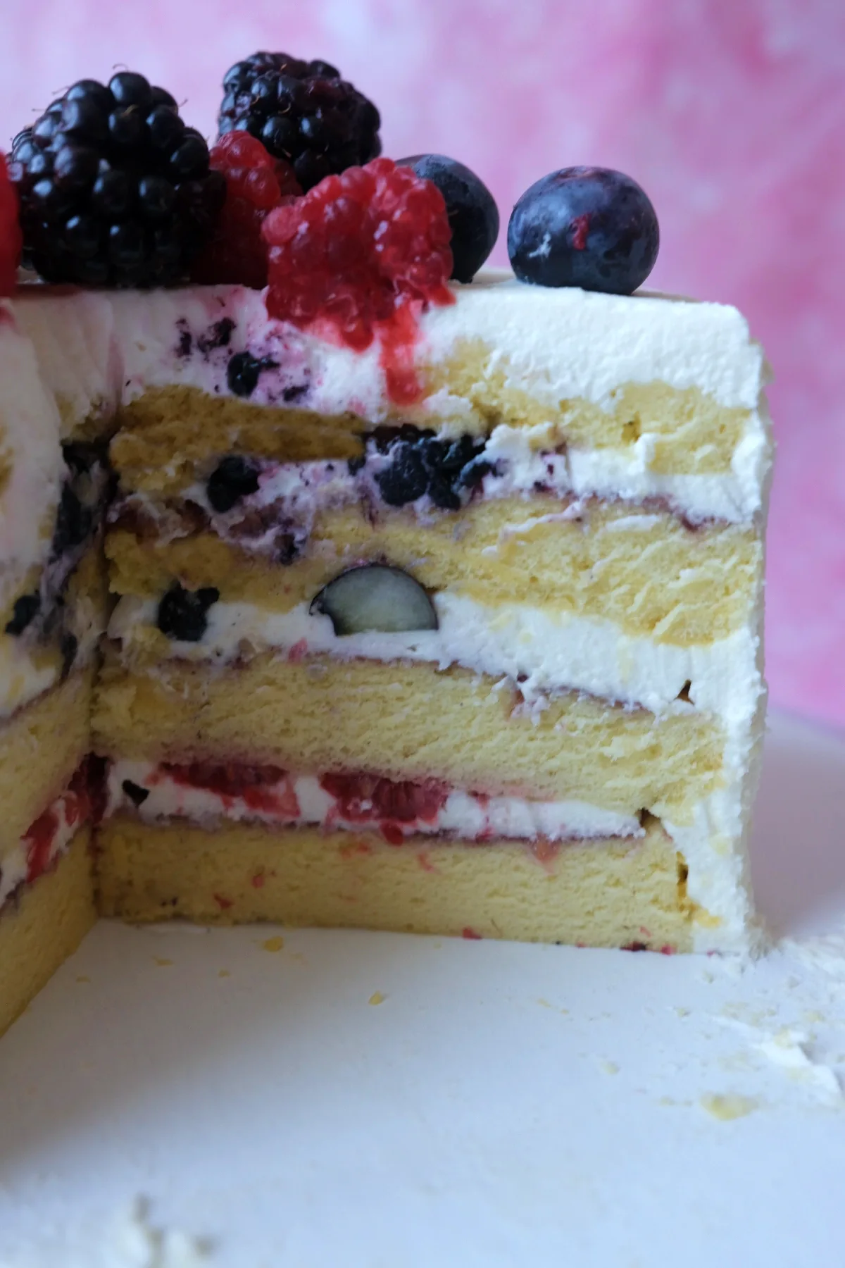 Berry chantilly cake with one slice removed, revealing soft chiffon cake layers and berry-filled chantilly cream frosting.