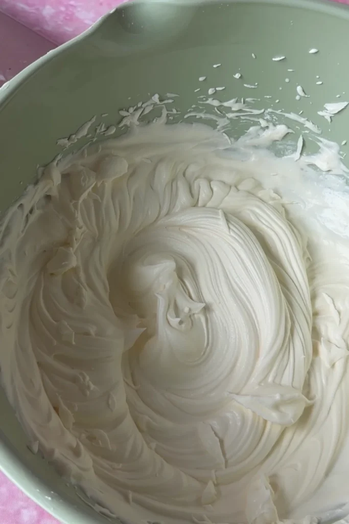 Smooth and fluffy mascarpone chantilly cream frosting swirled in a mixing bowl.