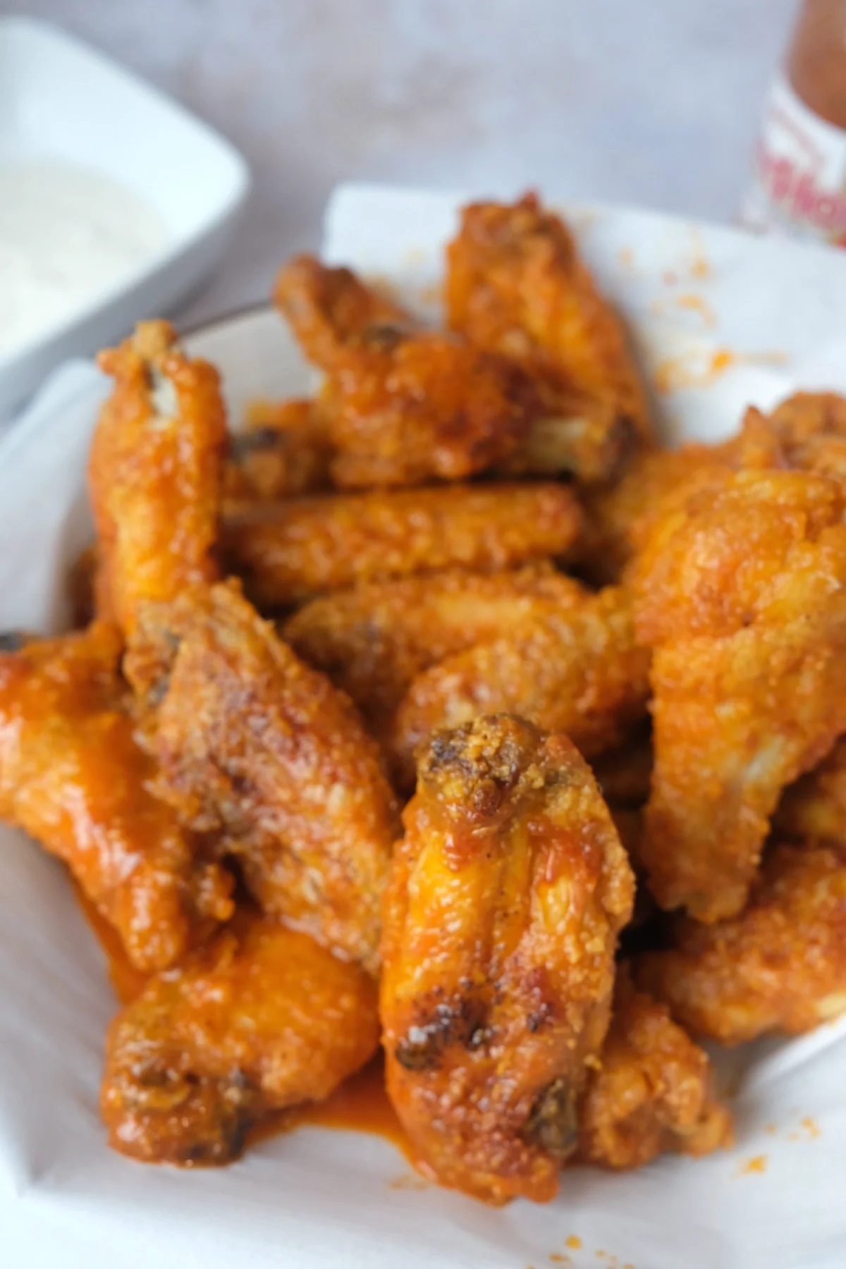 Close-up of crispy buffalo wings made in the air fryer with crunchy edges and tangy orange buffalo sauce.