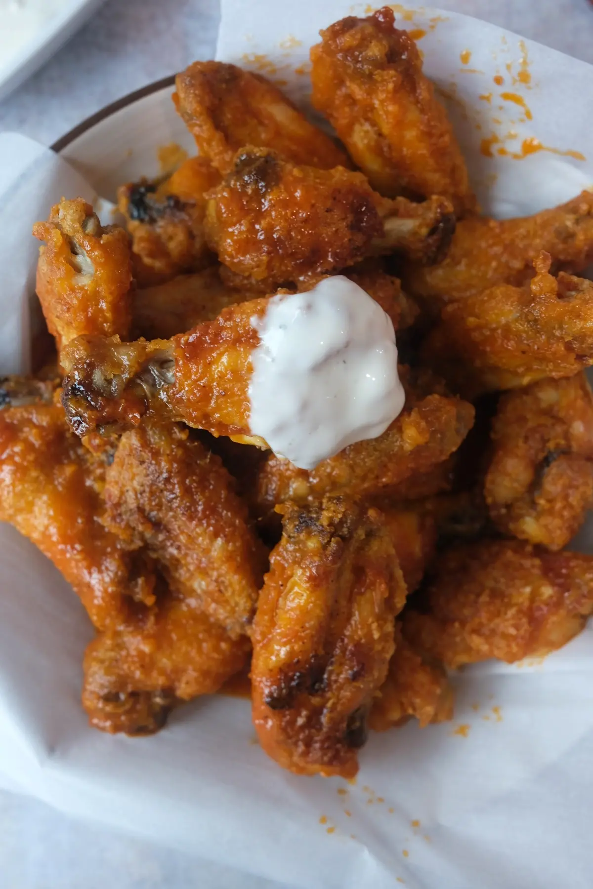 Close-up of crispy buffalo wings fresh from the air fryer with buttery hot sauce coating and ranch dip.