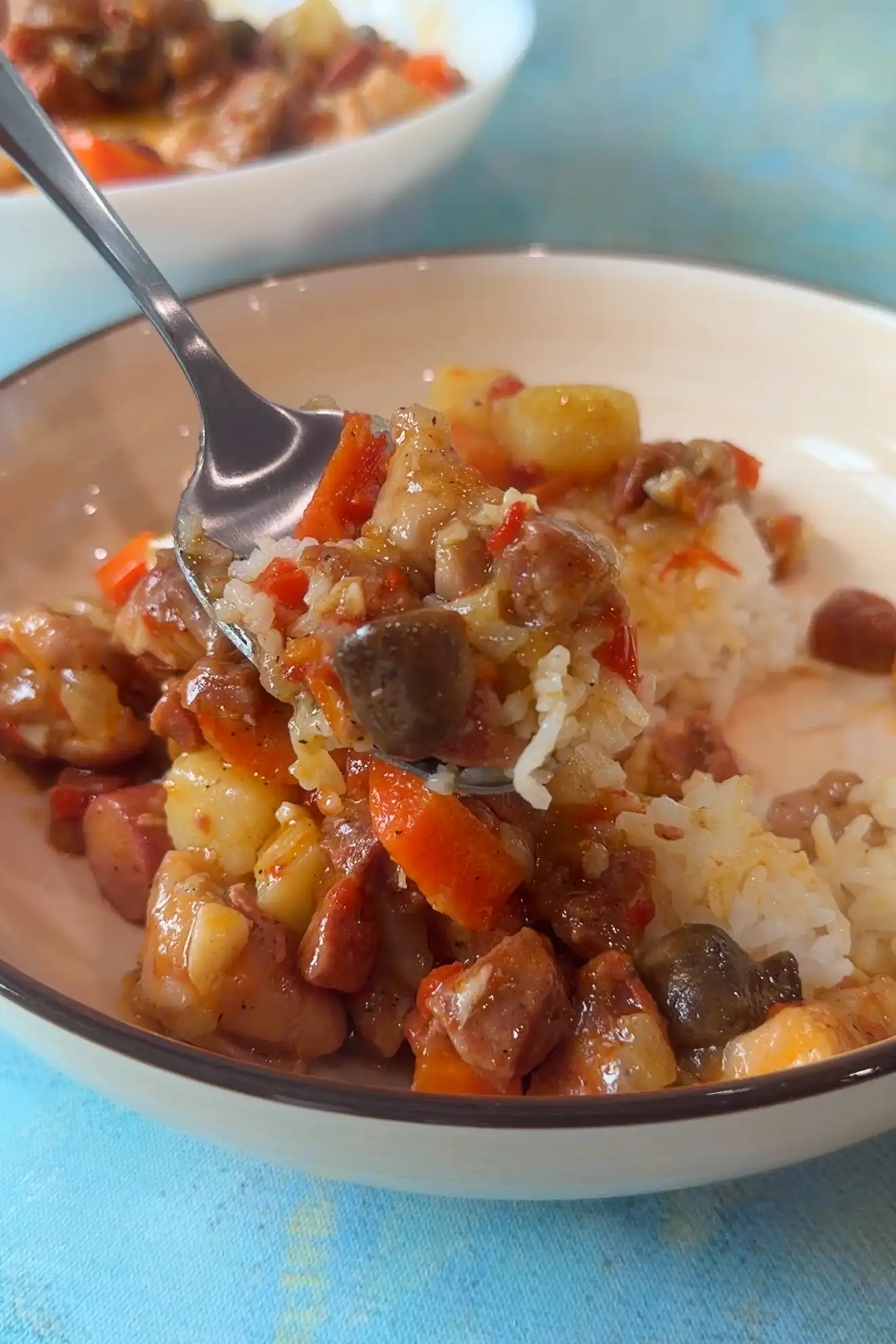 Spoonful of chicken pastel and rice with tender chicken, vegetables, mushrooms, and chorizo in a savory sauce.