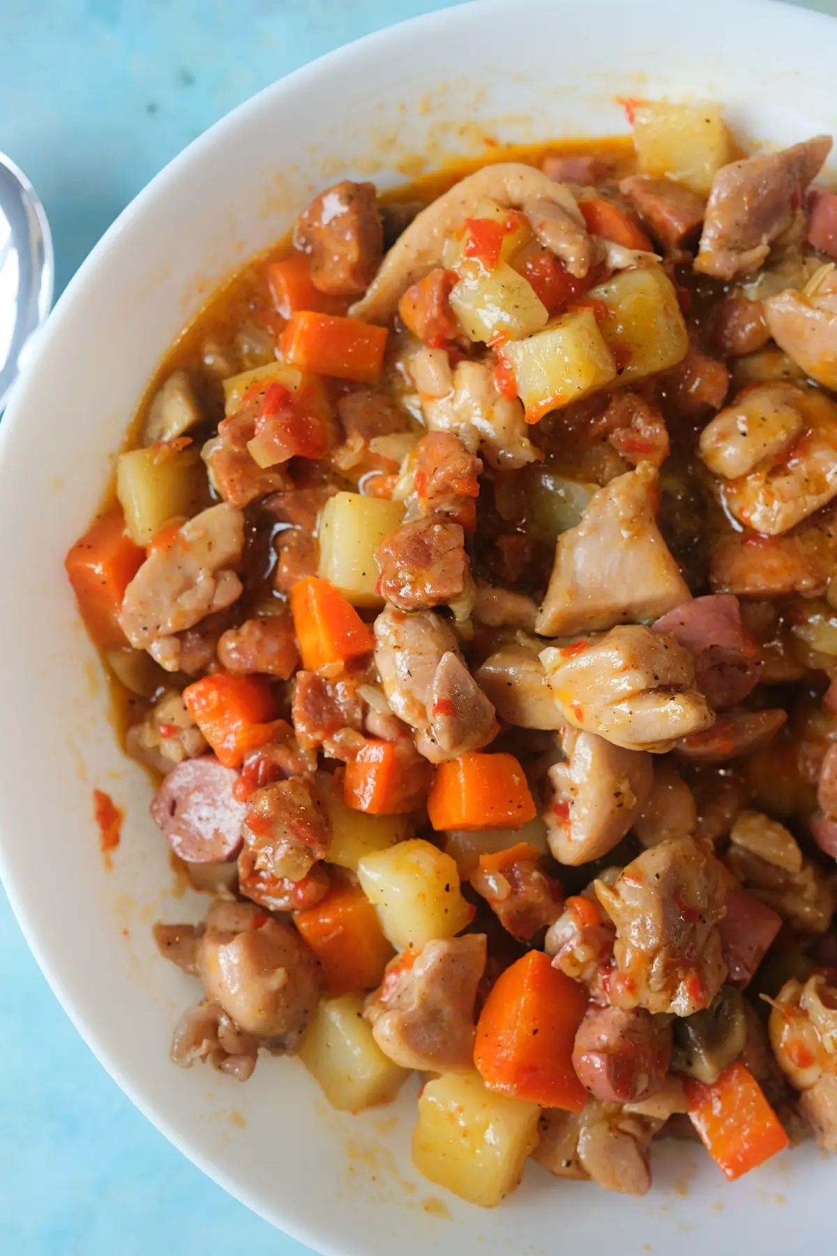 Close-up of homemade Filipino chicken pastel with tender chicken, vegetables, mushrooms, and sausage in a rich sauce.