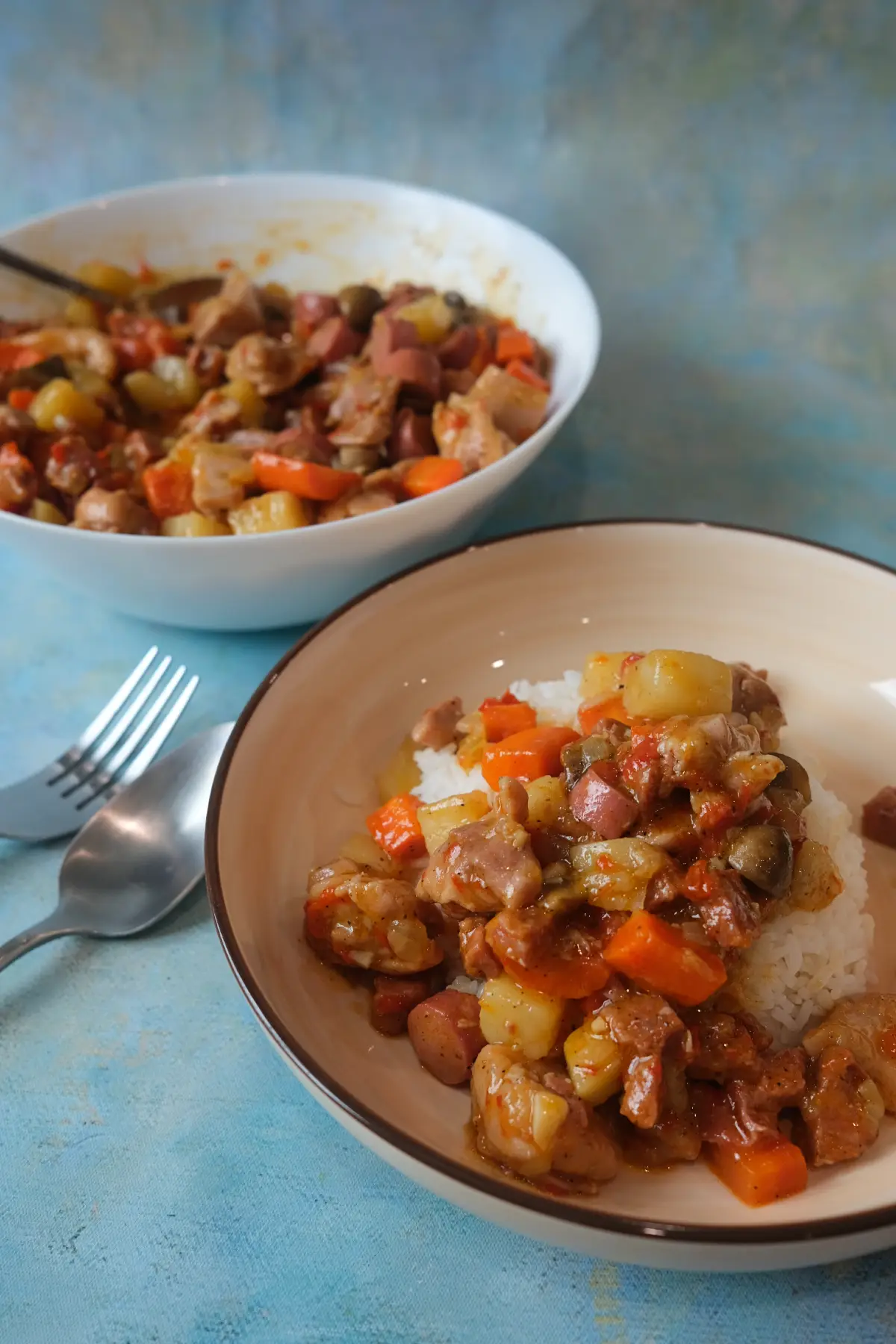 Plate of rice topped with Filipino chicken pastel, with carrots, potatoes, mushrooms, and sausage visible in every bite.