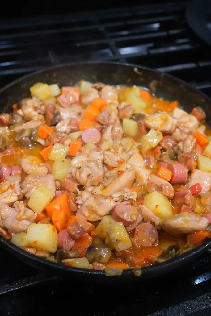 Finished Filipino chicken pastel with melted cheese, chicken, potatoes, carrots, mushrooms, chorizo, and Vienna sausages in a rich savory sauce.