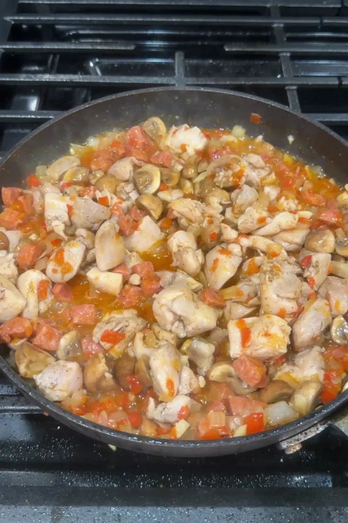 Chicken returned to the skillet and simmering with mushrooms, chorizo, onions, and bell peppers in a savory sauce.