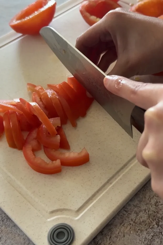Slicing and chopping fresh tomatoes into small pieces for chunky salsa.