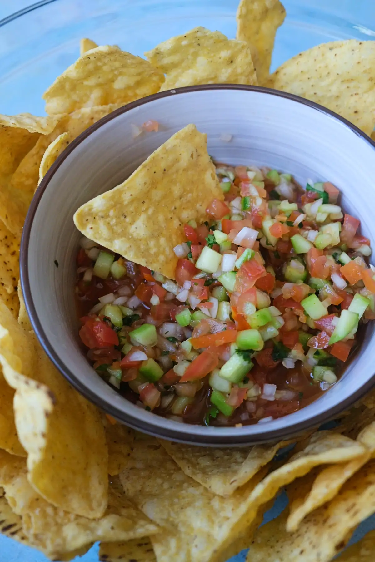 Bowl of chunky homemade salsa served with tortilla chips for dipping.