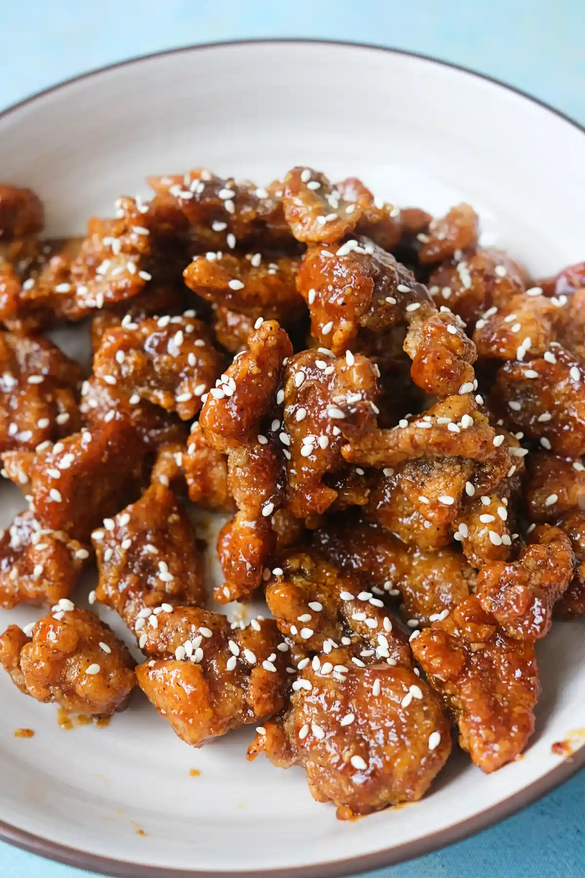 Close-up of crispy honey garlic chicken coated in glossy sauce and topped with sesame seeds.