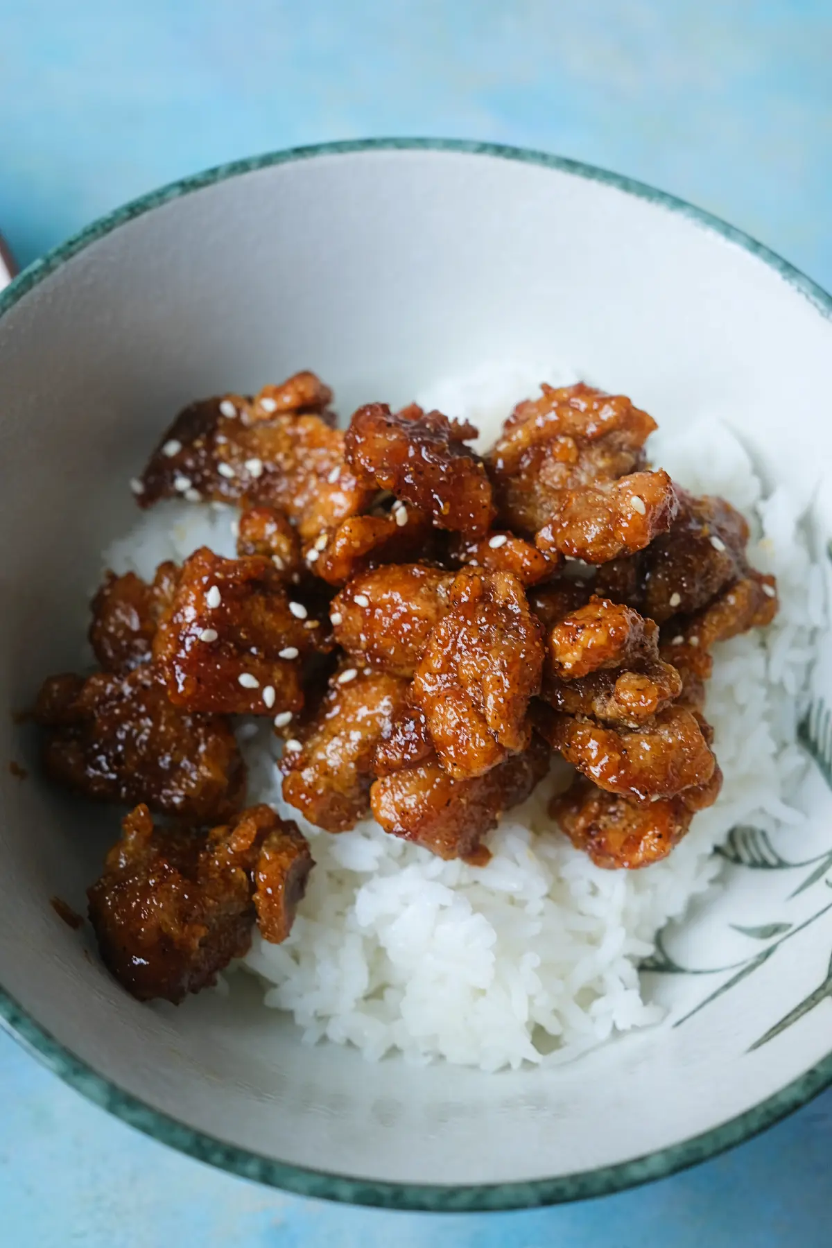 Bowl of sticky honey garlic chicken over steamed white rice.