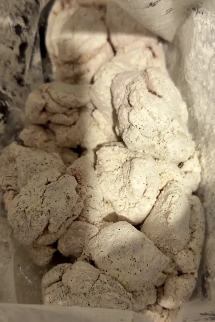 Chicken pieces coated in seasoned cornstarch inside a zip-top bag before air frying.