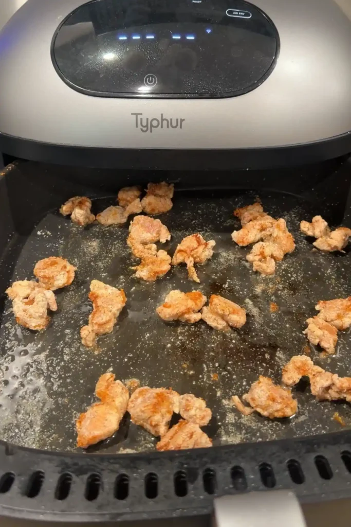 Crispy coated chicken cooking in an air fryer basket halfway through cooking.
