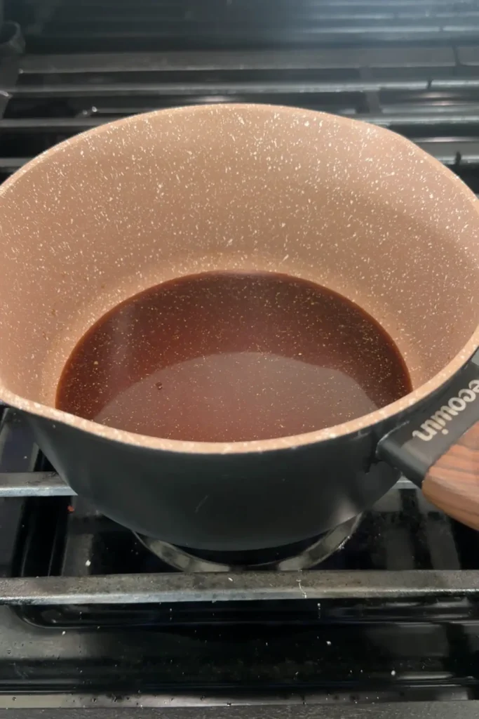 Honey garlic sauce simmering in a saucepan on the stove.