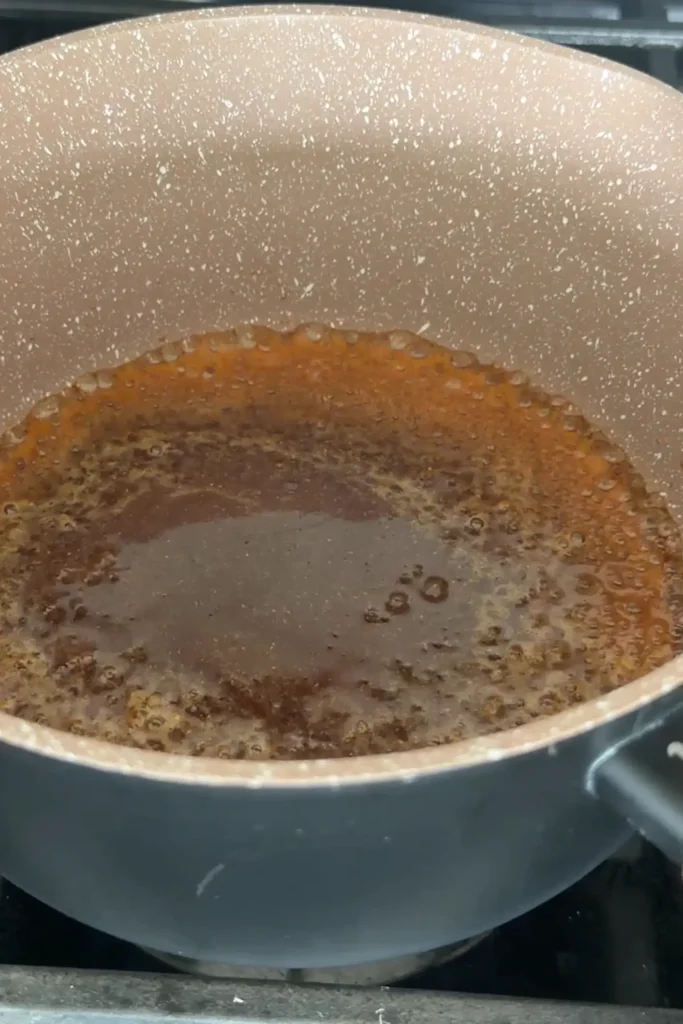 Honey garlic sauce bubbling and thickening in a saucepan.