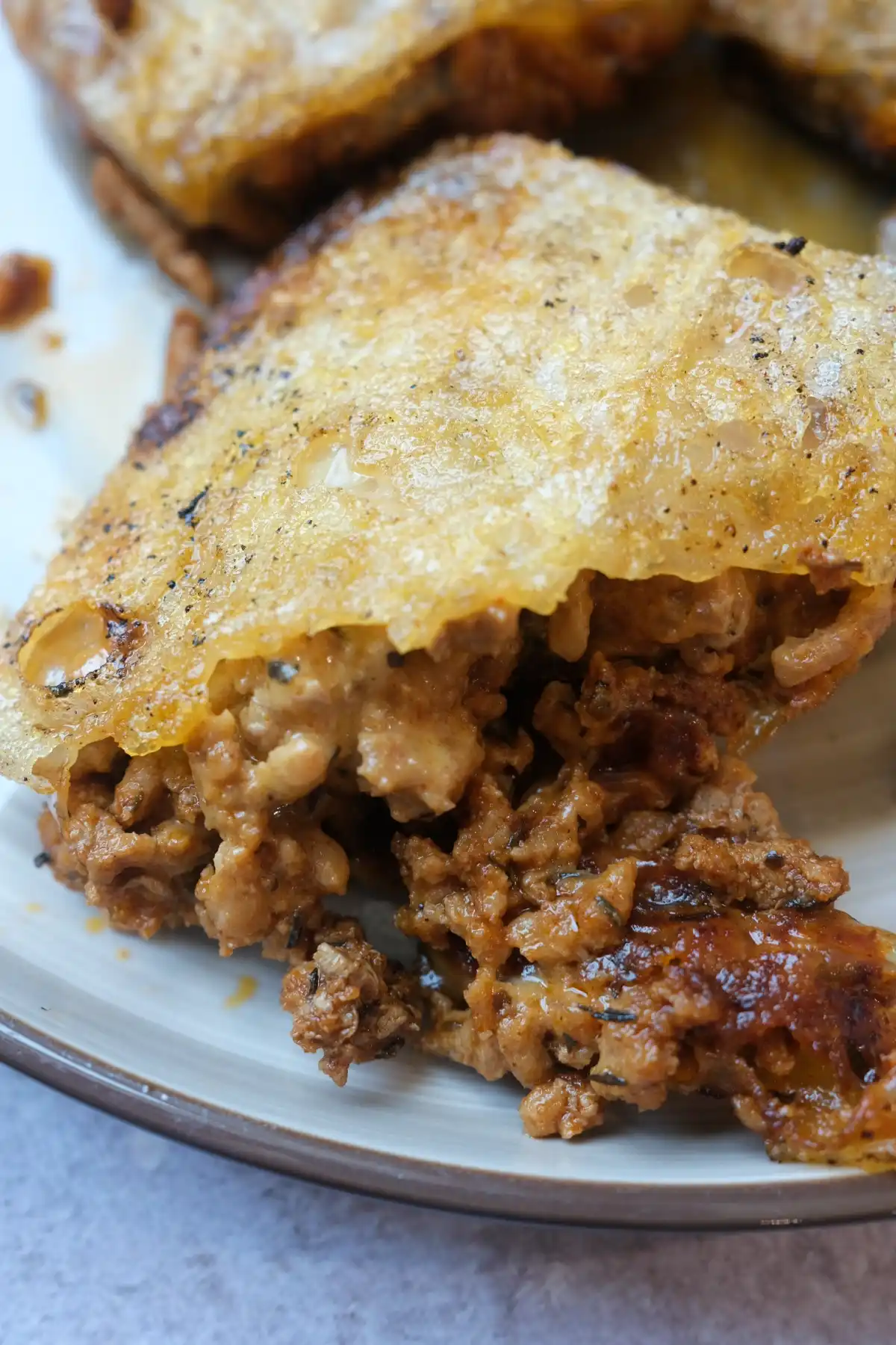 Close-up of crispy rice paper dumpling filled with cheesy seasoned pork on a plate.