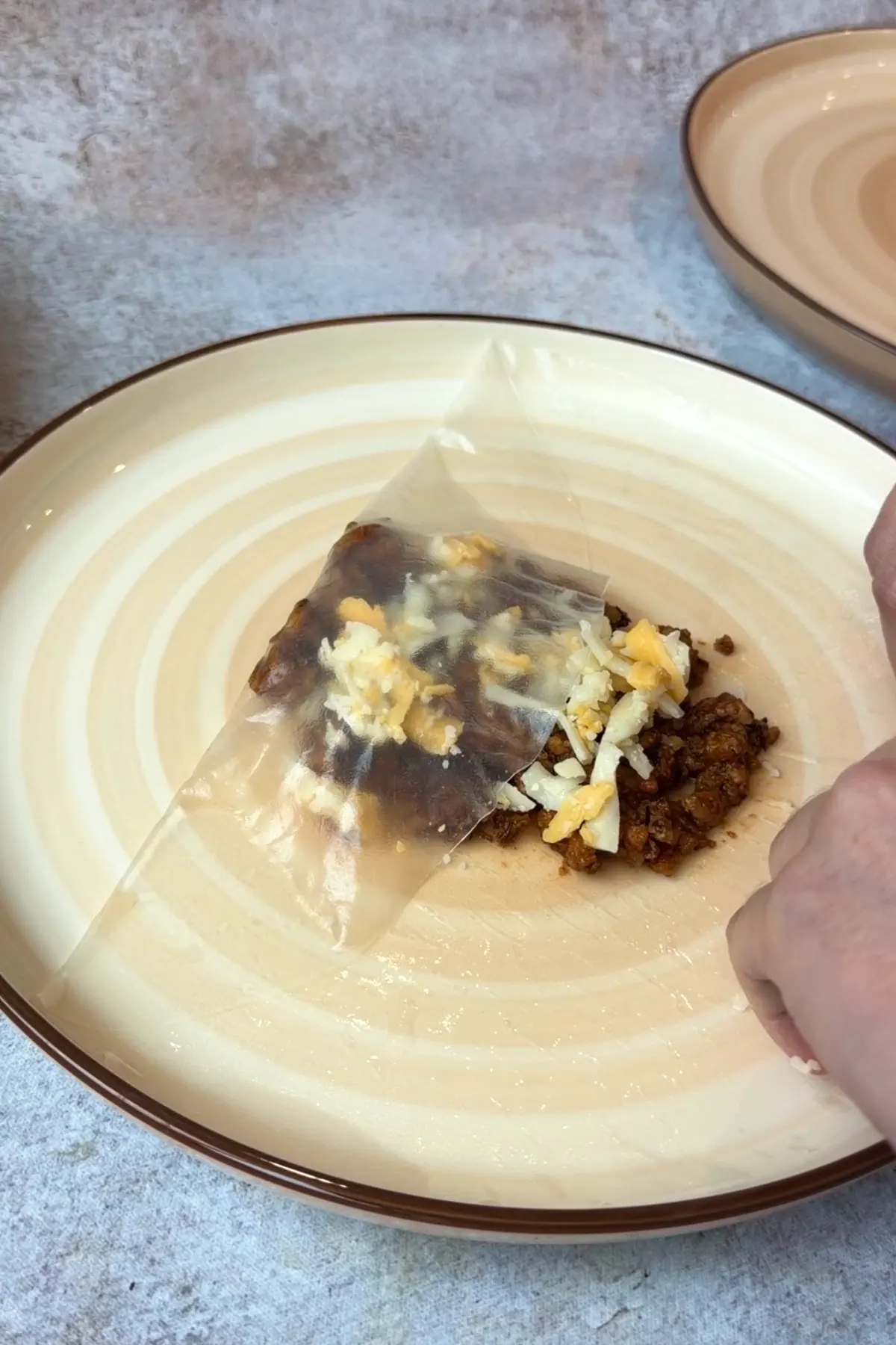Folding softened rice paper wrapper around seasoned pork and grated cheese filling.