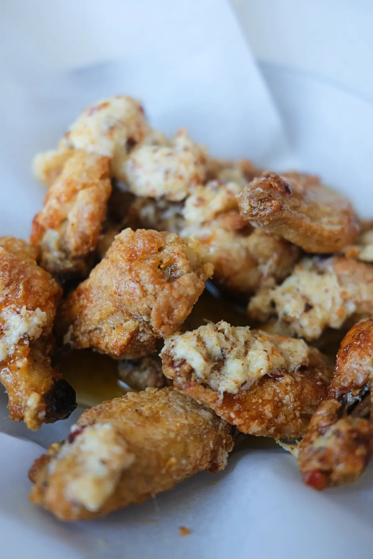 Detailed close-up of crunchy garlic parmesan wings with buttery parmesan sauce and red chili flakes.