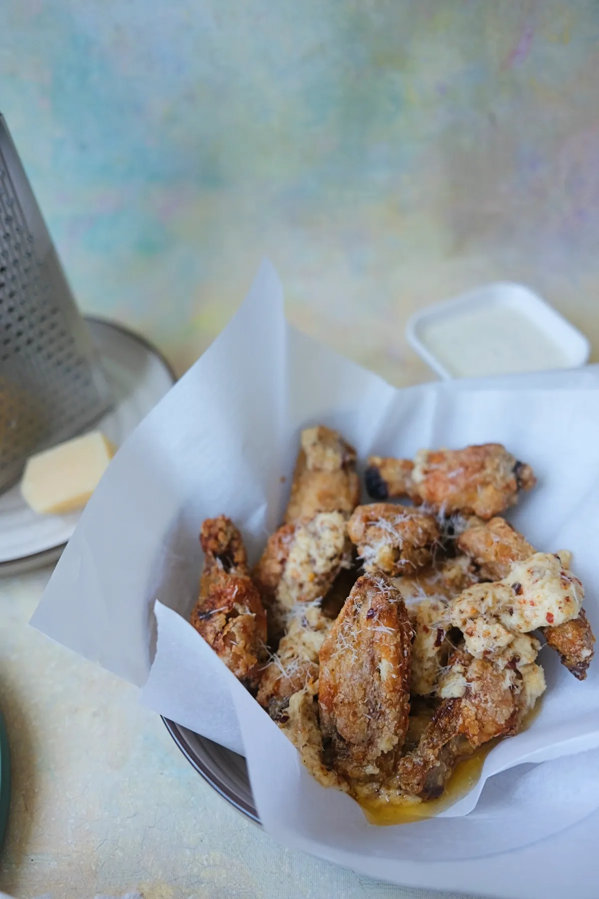 Garlic parmesan chicken wings served in a bowl with buttery sauce pooling underneath the crispy coating.
