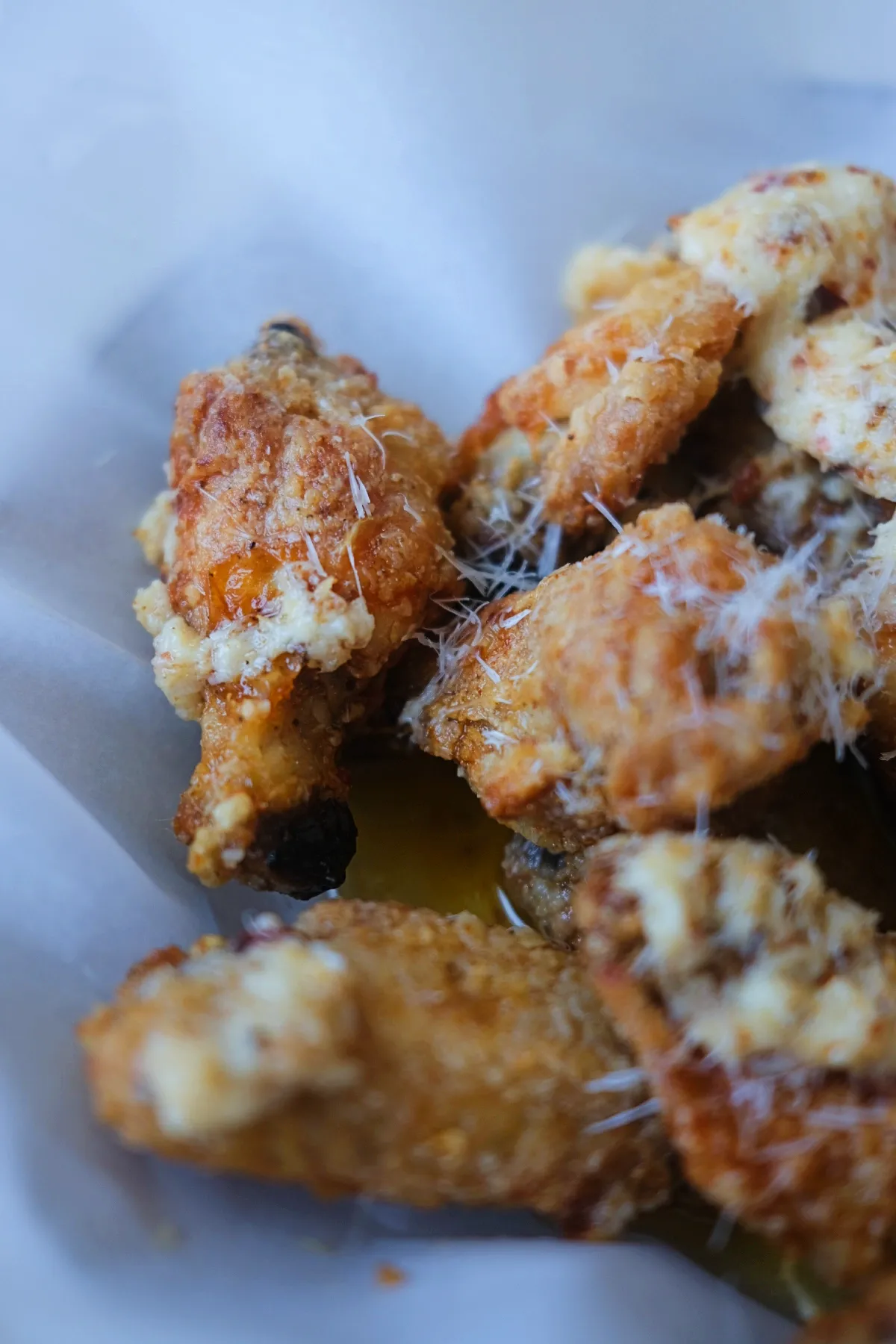 Air fryer garlic parmesan wings with crunchy coating, melted parmesan sauce, and red pepper flakes.