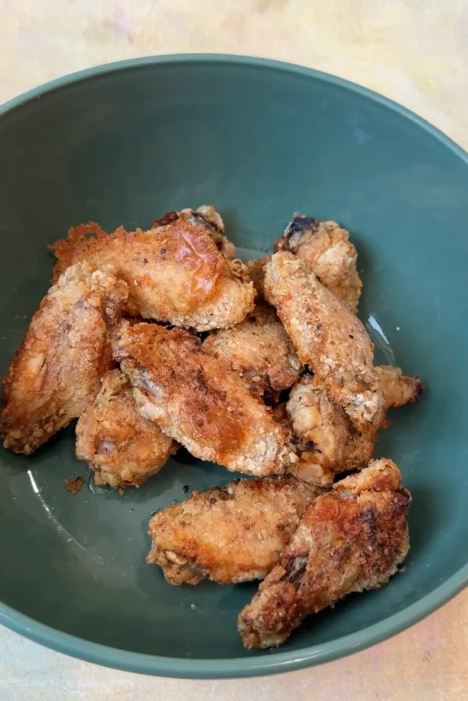 Crispy air fryer chicken wings in a bowl before adding garlic parmesan sauce.