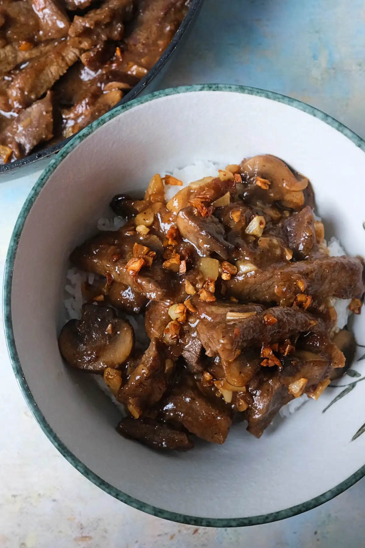 Close-up of Jollibee-style garlic pepper beef with mushrooms served over steamed rice.