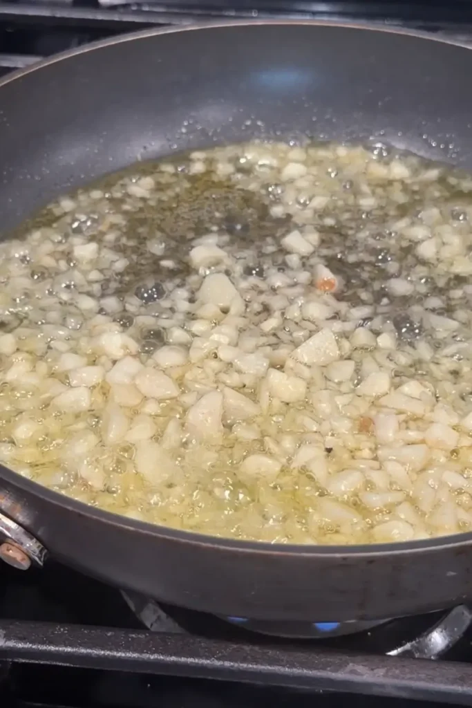Chopped garlic sizzling in hot oil in a nonstick skillet.