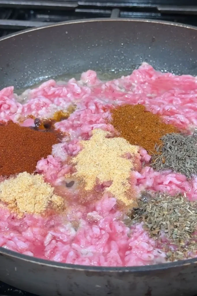Ground pork seasoned with smoked paprika, garlic powder, onion powder, thyme, and Italian seasoning in a pan.