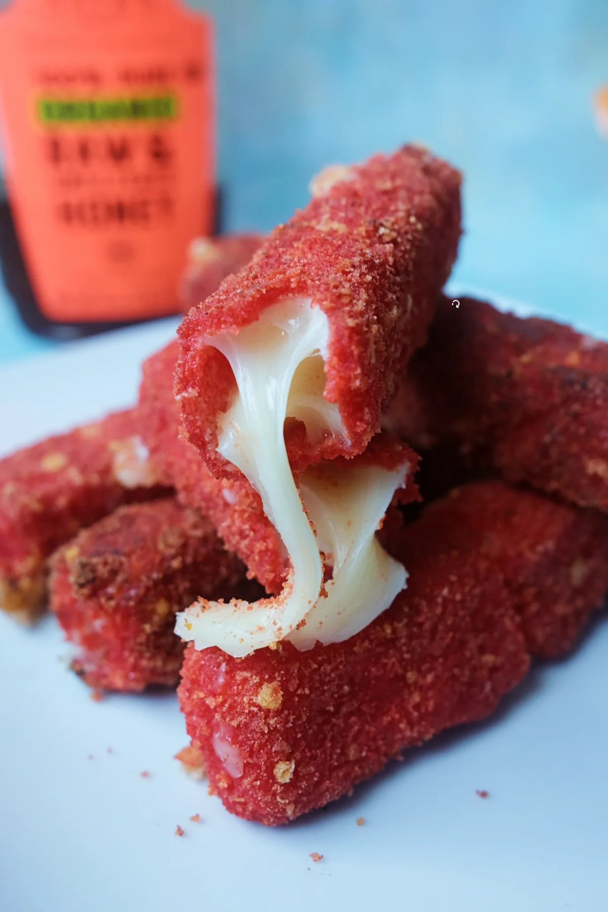 Close-up of a Hot Cheeto mozzarella stick with a dramatic melted cheese pull.