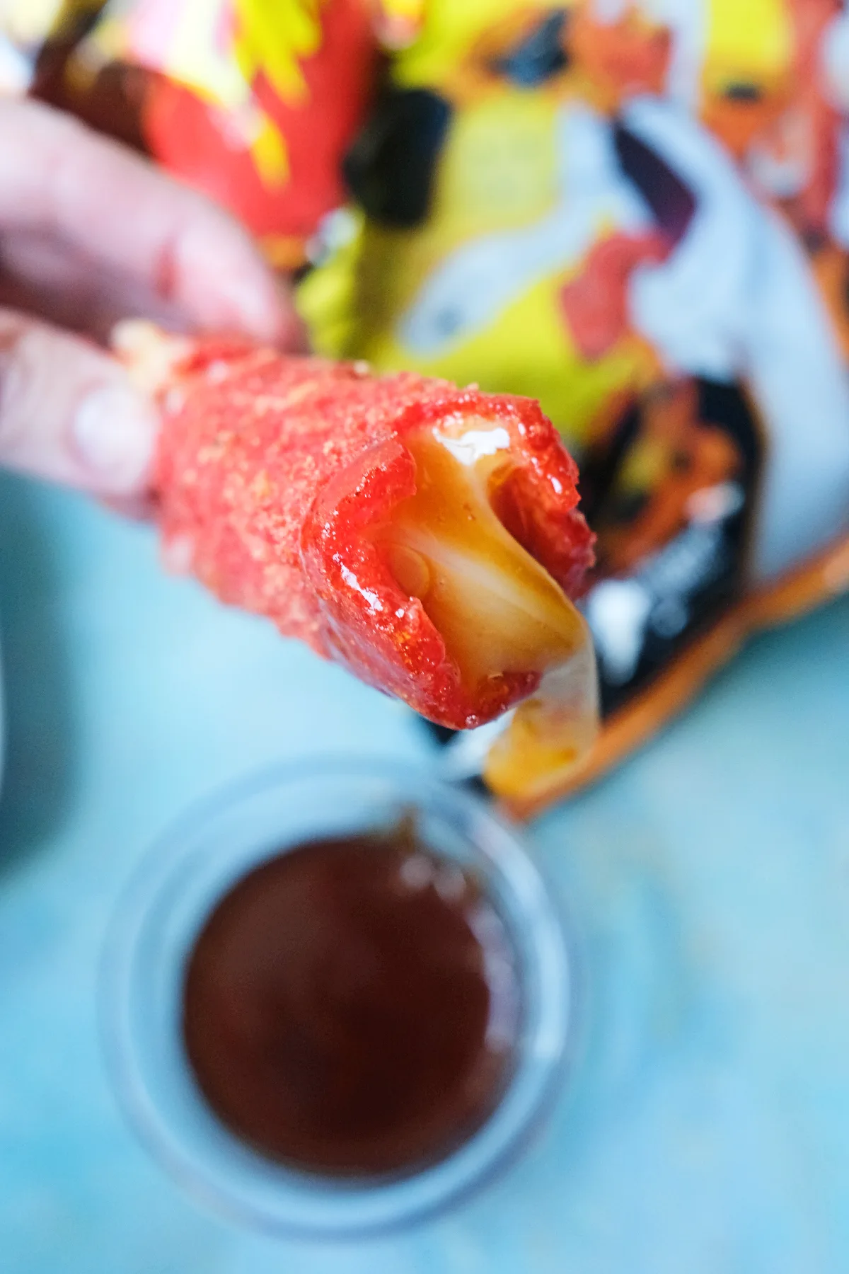 Close-up of crispy spicy Hot Cheeto mozzarella stick dipped in hot honey with melted mozzarella center.
