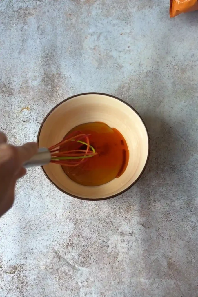 Whisking hot honey sauce in a bowl for spicy mozzarella stick dipping sauce.