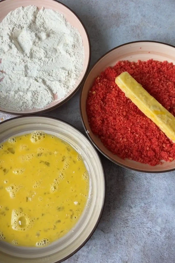 Mozzarella stick coated in egg wash and crushed Hot Cheetos during the breading process.