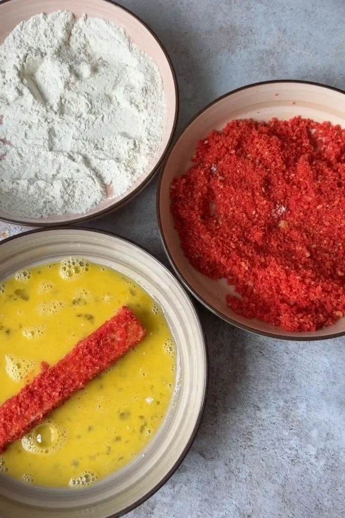 Hot Cheetos-coated mozzarella stick dipped back into beaten eggs for a second coating.