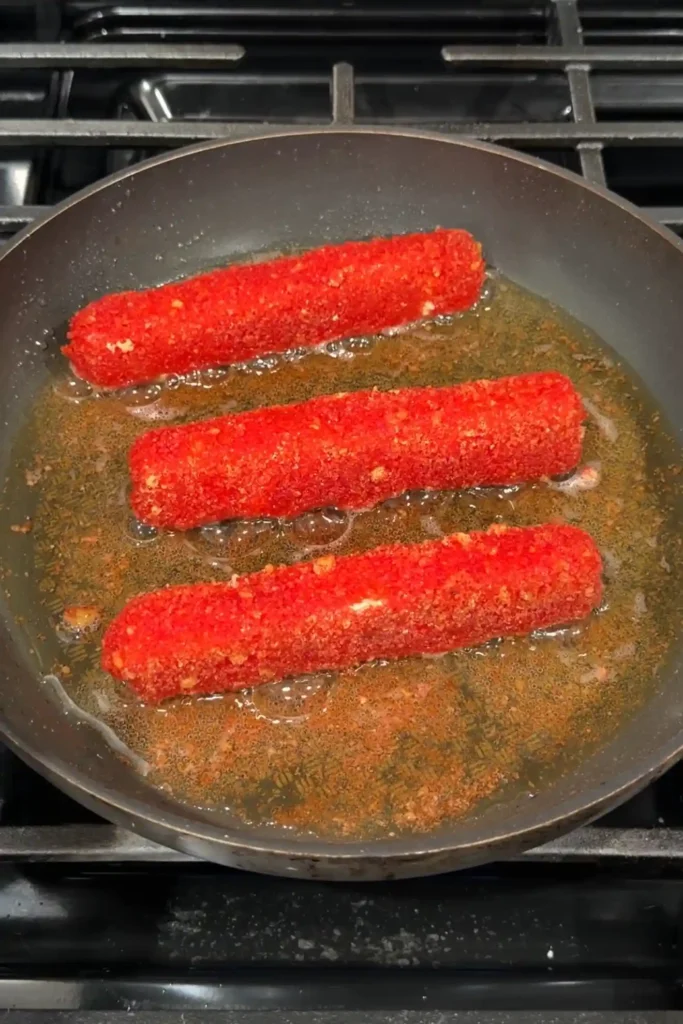 Crispy Hot Cheetos mozzarella sticks frying in shallow oil until golden and crunchy.