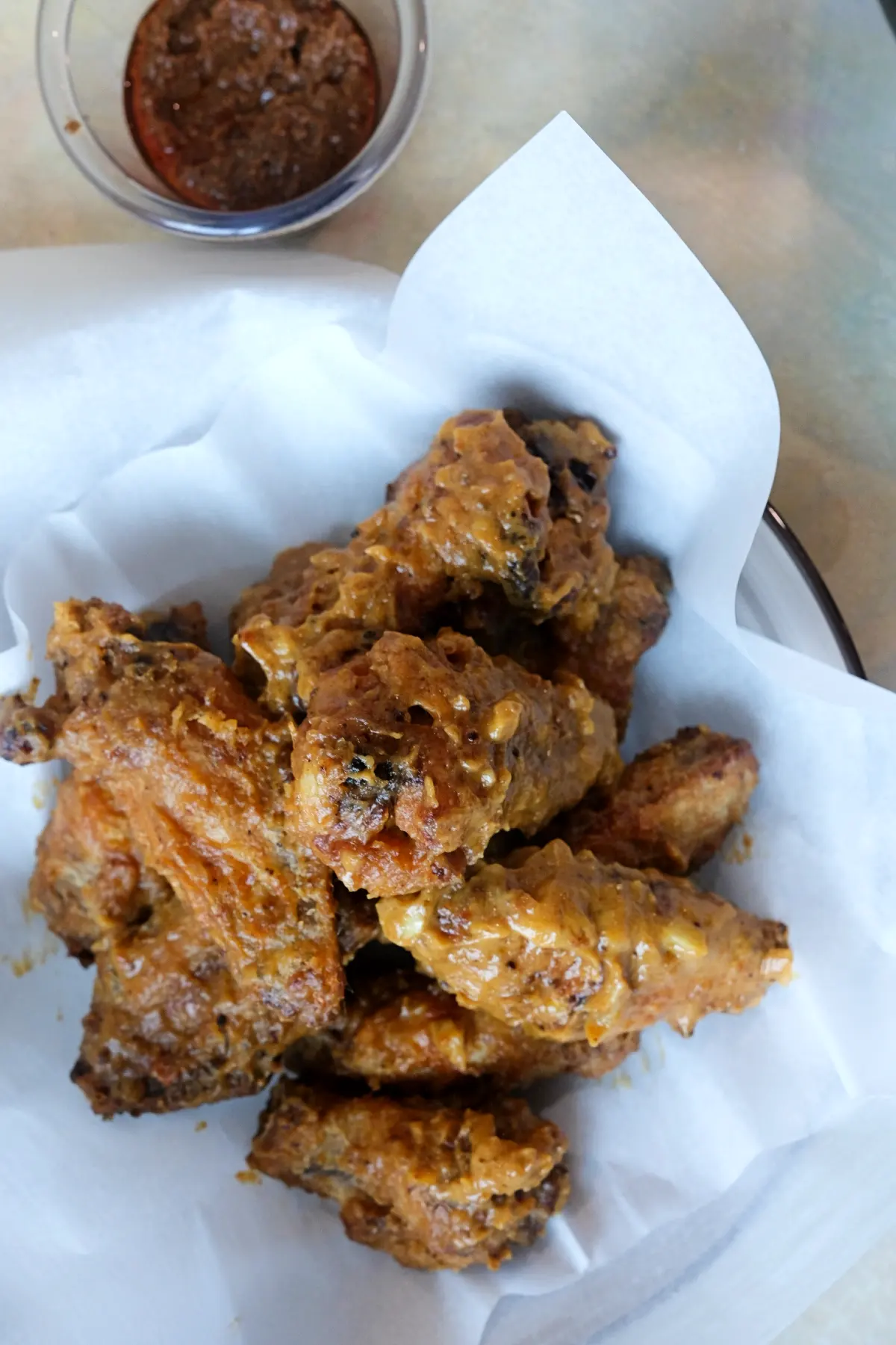 Bowl of crispy air fryer chicken wings coated in savory kare kare sauce made with peanut butter and bagoong.