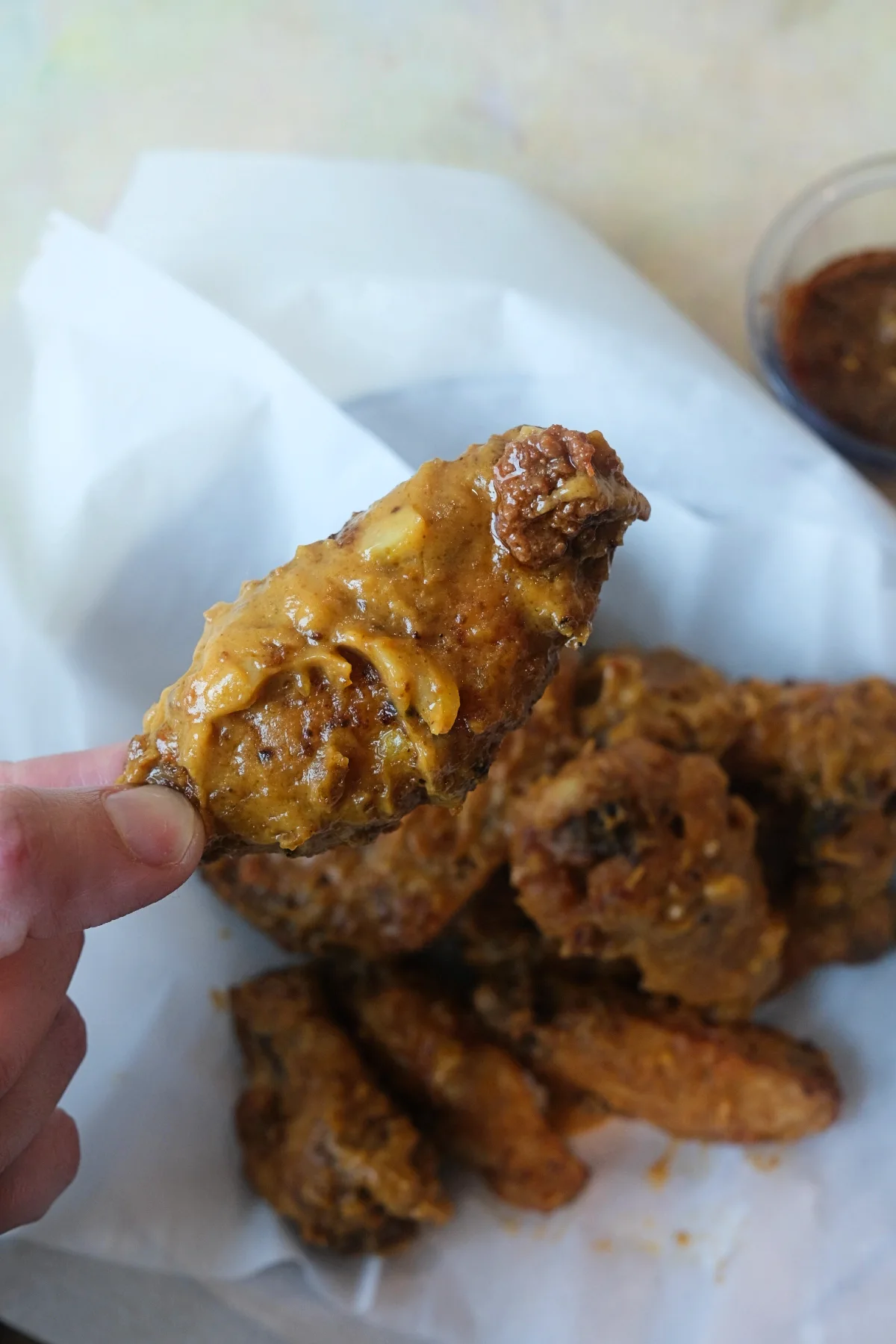 Close-up of a crunchy chicken wing covered in rich kare kare peanut sauce with bagoong.