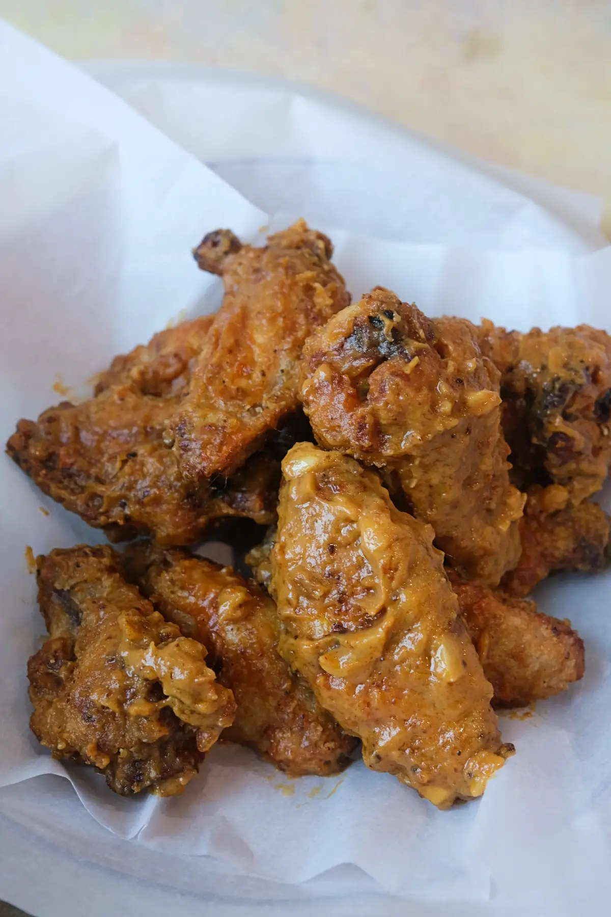 Crispy air fryer chicken wings coated in creamy kare kare sauce with visible garlic pieces and a golden brown crust.