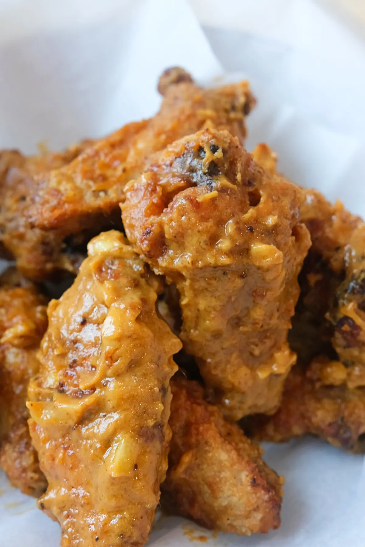 Detailed close-up of crunchy air fryer chicken wings covered in thick kare kare peanut sauce.